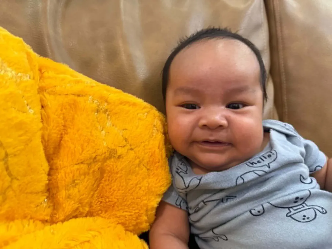 Baby Louis smiling by a yellow blanket