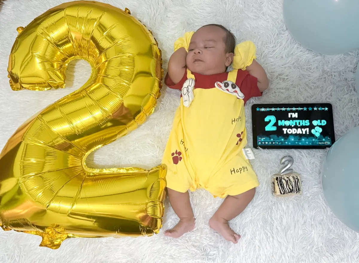 Baby Louis asleep beside a gold number two balloon